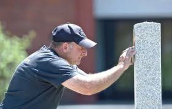 Lee Teicholz, Project Organizer for the Veterans Walkway of Honor, installs a bronze plaque on one of a dozen granite pillars that he installed along the walkway at the Danbury War Memorial.