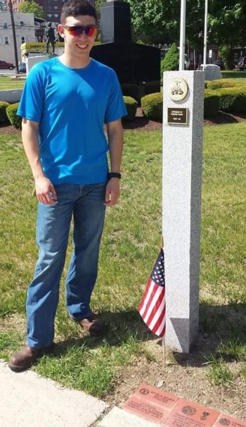 Airman First Class Ryan Maher with the USAF 377th Security Forces Squadron standing next to his brick and one of the recently installed granite pillars. Ryan was honored with a brick for his service by his mother and father. 